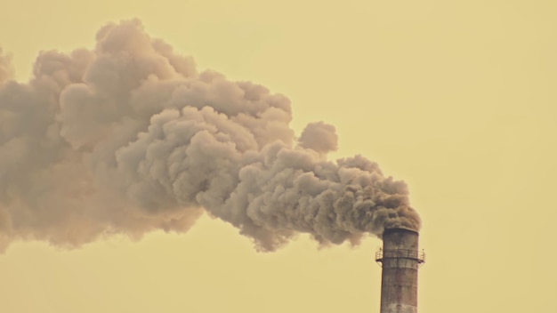 This smoke coming from the chimney in a factory. harmful\
emissions into the atmosphere, from the pipe. serious damage the\
environment. plant stack coaling station. close up shot. dark sad\
view.