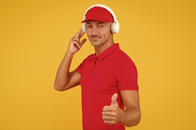 This song is so good unshaven man give thumbs up yellow background like and approval sign handsome guy listen to song modern life new technology enjoying song playing in headphones