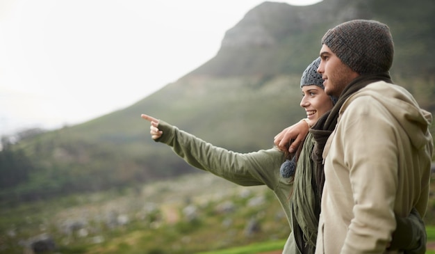 This view is stunning A young couple admiring the view while out hiking during winter