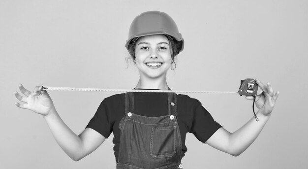 Foto questo sarà perfetto per i bambini indossare il casco sul cantiere edile teen girl builder con strumento di costruzione metro a nastro bambino sul lavoro di riparazione concetto di ristrutturazione in officina occupato falegname professionista