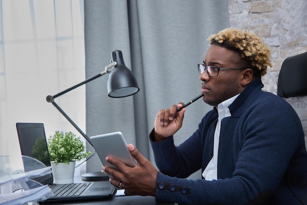 Thoughtful African man sitting at a table by the window