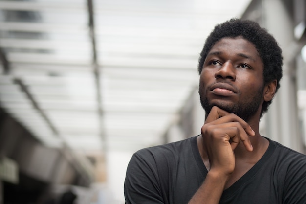 Photo thoughtful african man thinking; portrait of pensive young adult african man thinking about plan, idea, future, brain storming concept; west african young adult man model