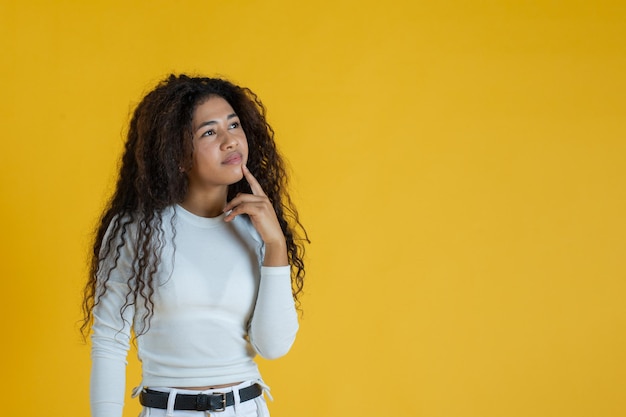 Thoughtful afro-american woman studio shot with yellow background