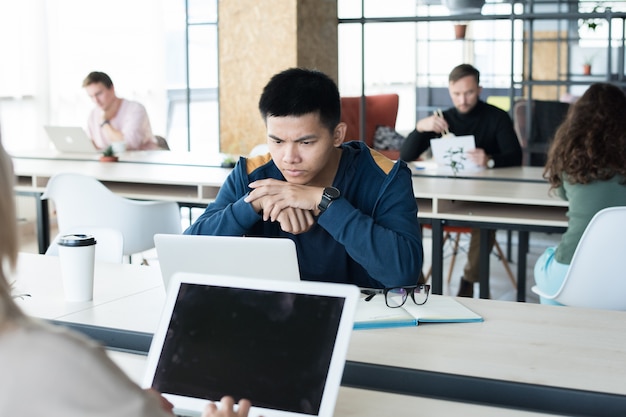 Thoughtful Asian student in coworking space