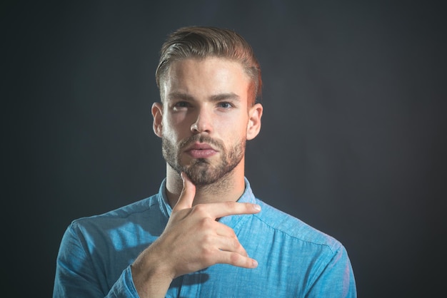 Thoughtful attractive unshaven man with stylish hair hold hand on chin thinking bearded man wearing