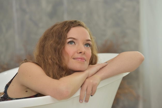 Photo thoughtful beautiful woman looking away while sitting in bathtub at home