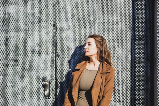 Photo thoughtful beautiful young woman standing against wall