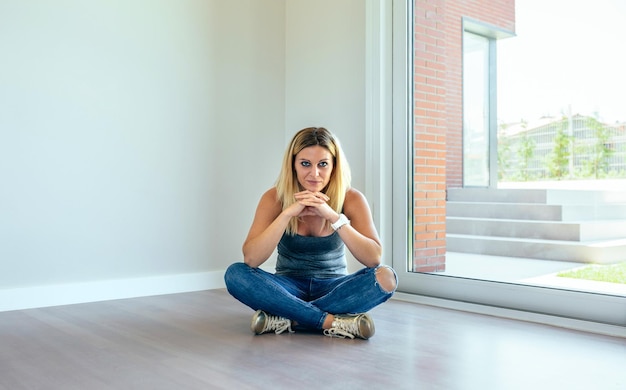 Thoughtful blonde girl sitting in a empty living room