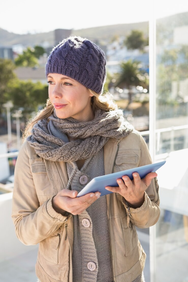 タブレットを使用して暖かい服で思慮深い金髪
