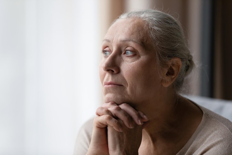 Photo thoughtful bored older 70s woman looking at window feeling depressed frustrated lonely suffering form memory loss dementia alzheimer disease mental disorder old age problems concept