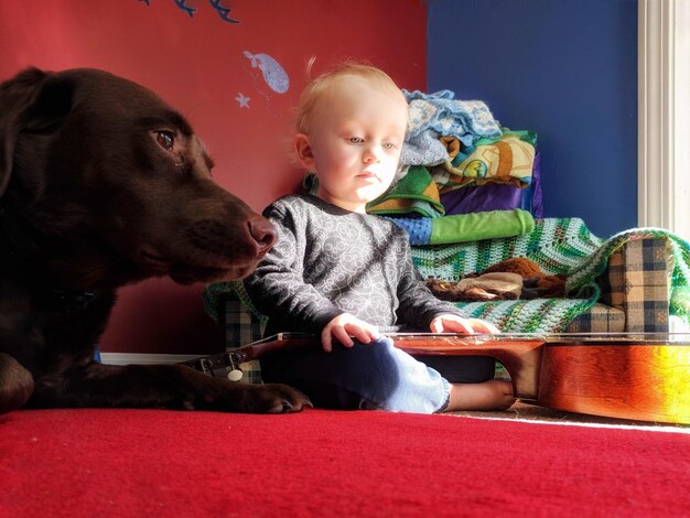 Photo thoughtful boy playing with guitar by dog at home