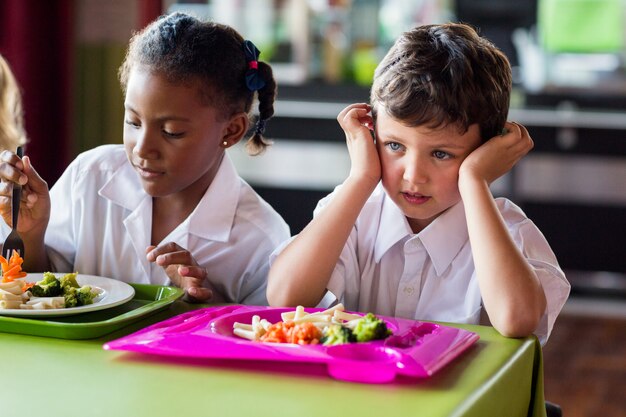 Thoughtful boy with classmates in canteen