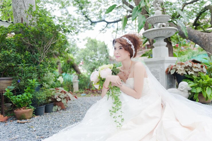 Photo 庭に座っている間,花束を握っている思慮深い花嫁