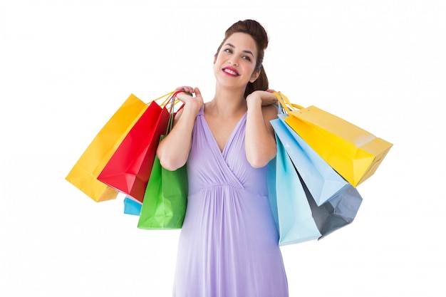 Thoughtful brunette holding shopping bags on white background