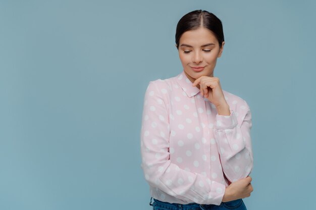 Thoughtful brunette lady holds chin