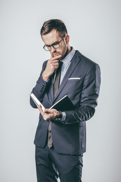 Thoughtful businessman reading notepad