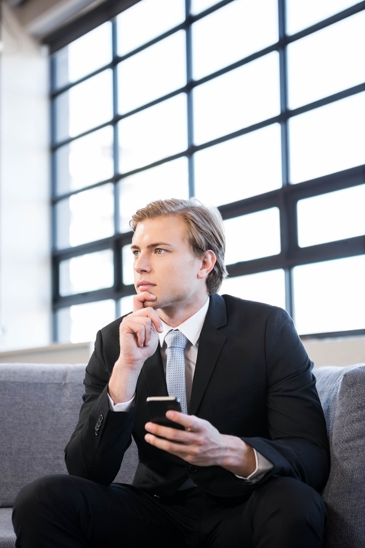 Photo thoughtful businessman sitting on sofa and looking away in office