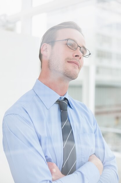 Thoughtful businessman standing with arms crossed