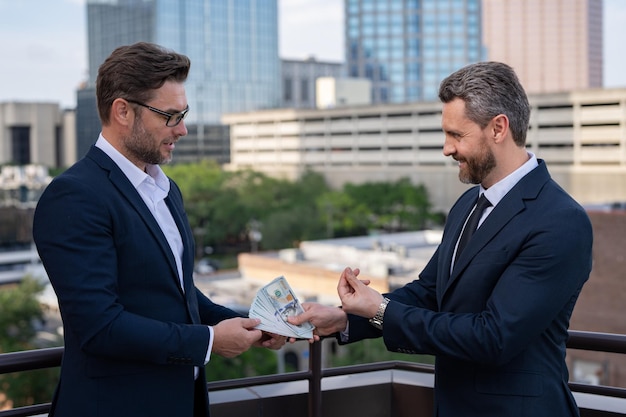 Thoughtful businessman wearing a suit front of office outdoor business men giving money business man