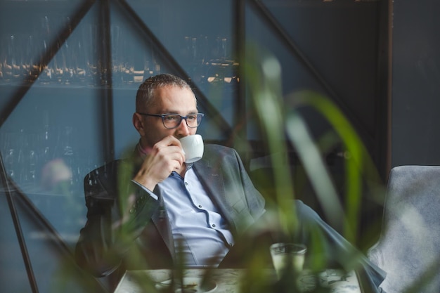 Photo thoughtful businessman with coffee on table sitting at restaurant