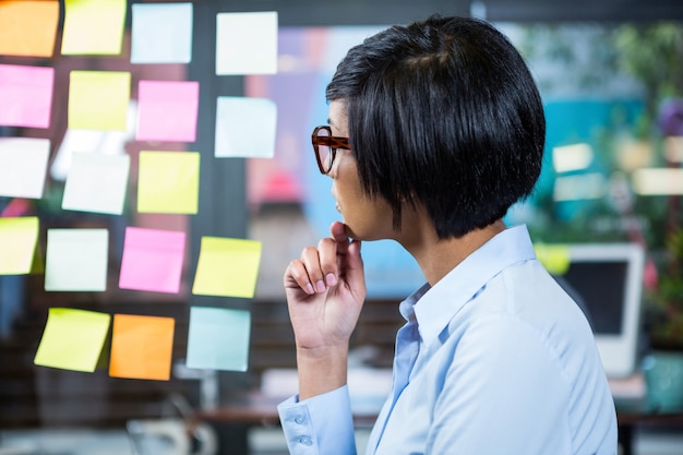 Thoughtful businesswoman looking at sticky notes