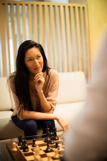 Thoughtful businesswoman playing chess with male colleague