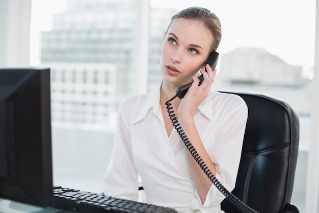 Thoughtful businesswoman sitting at desk on the phone