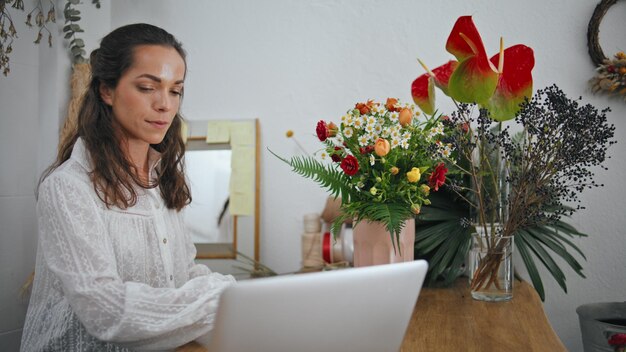 Photo thoughtful businesswoman type computer laptop in flower store work concept