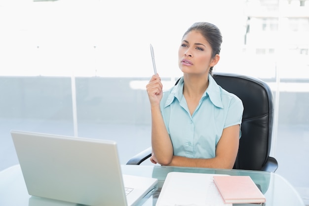 Thoughtful businesswoman using laptop in office