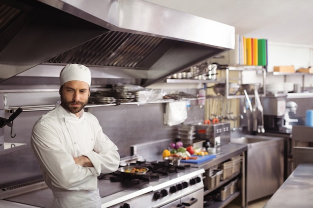 Foto chef premuroso in piedi in cucina commerciale