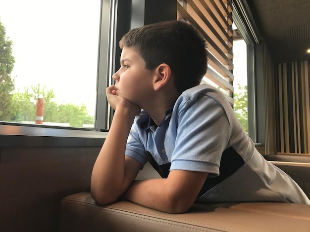 thoughtful child looking through the window. Kid thinking about the future or worried