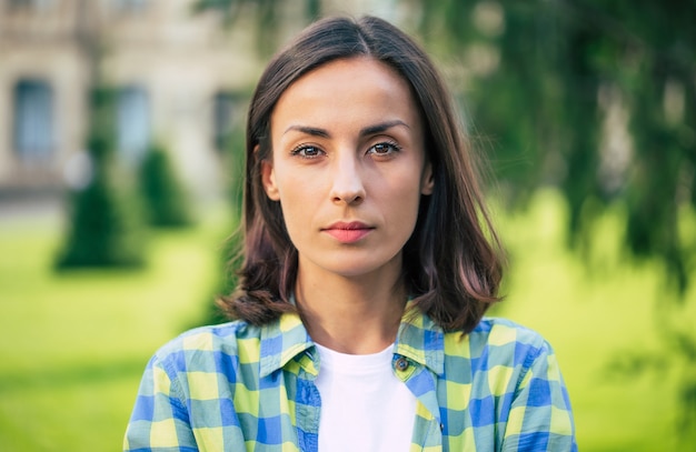 Thoughtful confident girl. Portrait of a young beautiful confident brunette woman in a checkered shirt 