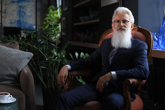 Thoughtful confident handsome businessman thinking while sitting on armchair in his modern office about business concept