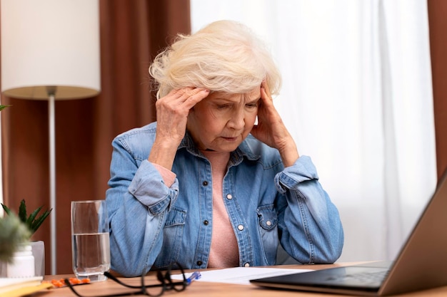 Thoughtful confused mature businesswoman concerned thinking about online problem looking at laptop Frustrated worried senior woman having headache suffering from memory loss