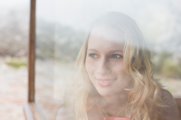 Thoughtful content woman looking out through window