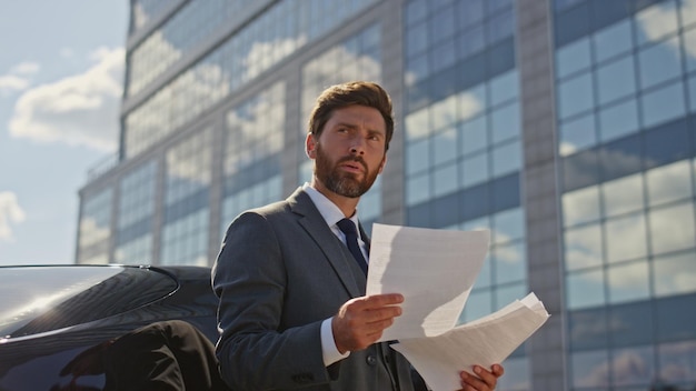 Thoughtful director reading contract at sunny business area boss looking deal