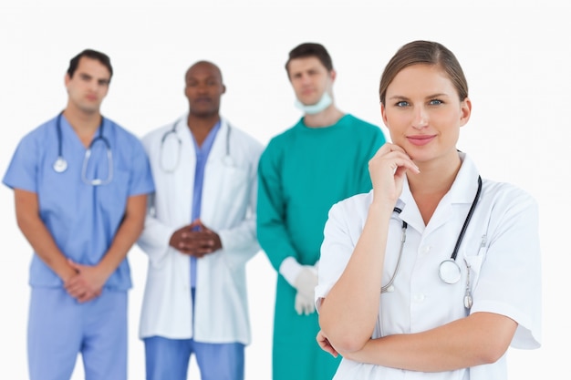 Thoughtful doctor with male colleagues behind her