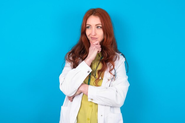 Thoughtful doctor woman holds chin and looks away pensively makes up great plan