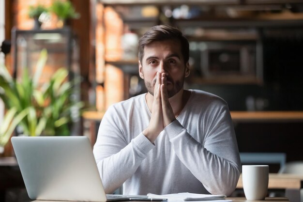 Thoughtful doubtful businessman in tension thinking make\
difficult decision at work stressed man put hands in prayer pray\
with hope pondering reflecting concerned about problem challenge\
sit at desk