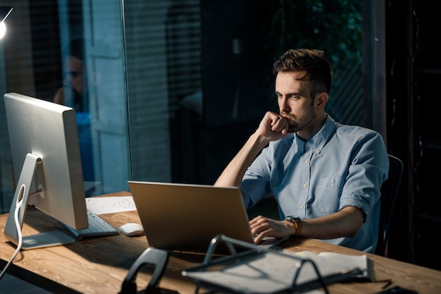 Thoughtful employee leaning on hand at laptop