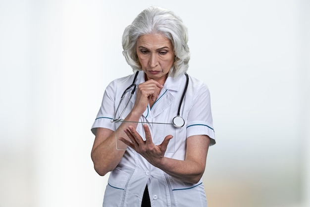 Thoughtful female doctor using transparent tablet pc.