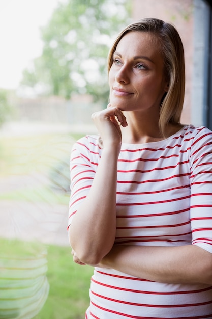 Thoughtful female student looking through the window at the university