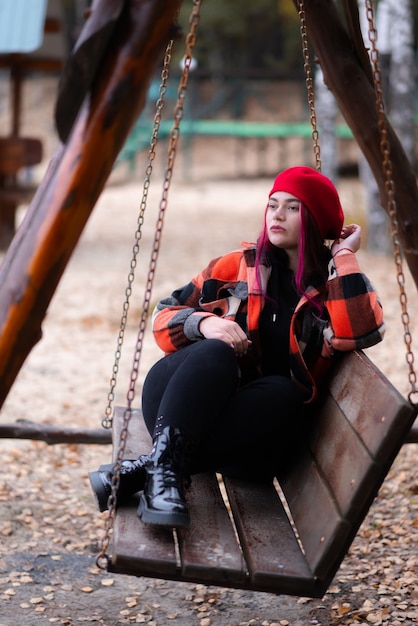 Thoughtful girl is relaxing in a swing in autumn