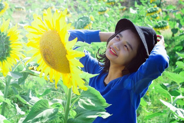 Thoughtful girl wearing hat while standing at sunflower farm