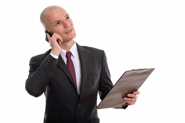 Задумчивый красивый лысый бизнесмен разговаривает по мобильному телефону