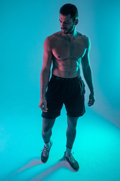 Thoughtful handsome bearded european young man. Guy with naked sportive torso. Isolated on blue background. Studio shoot