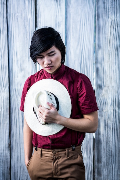 Thoughtful hipster holding a straw hat