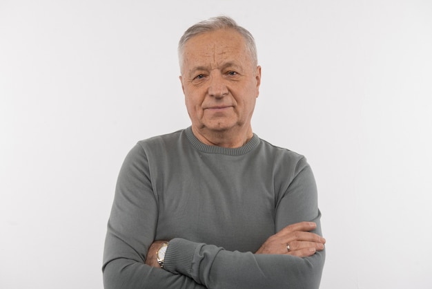 Thoughtful look. Nice aged man standing cross handed while looking at you