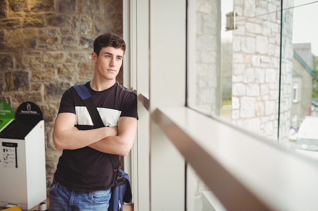 Thoughtful male student leaning on window