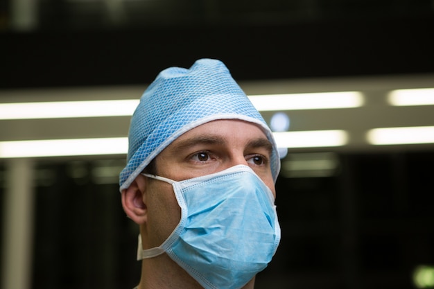 Вдумчивый мужчина-хирург в хирургической маске